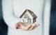 A midsection of a person holding a miniature house